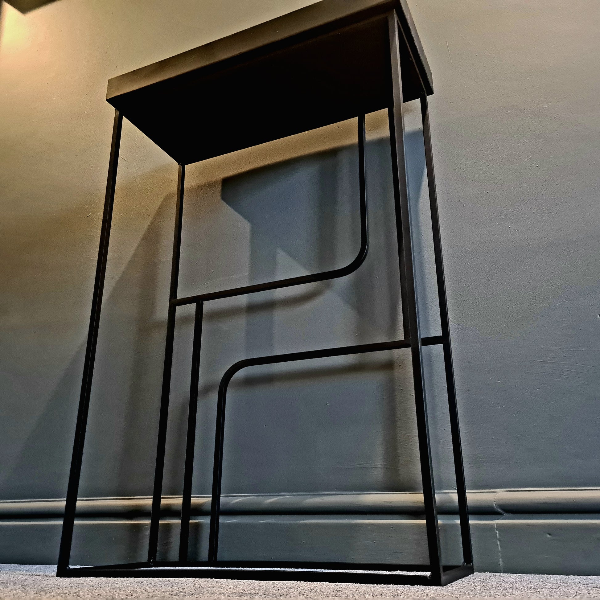 Black metal stool against a plain wall