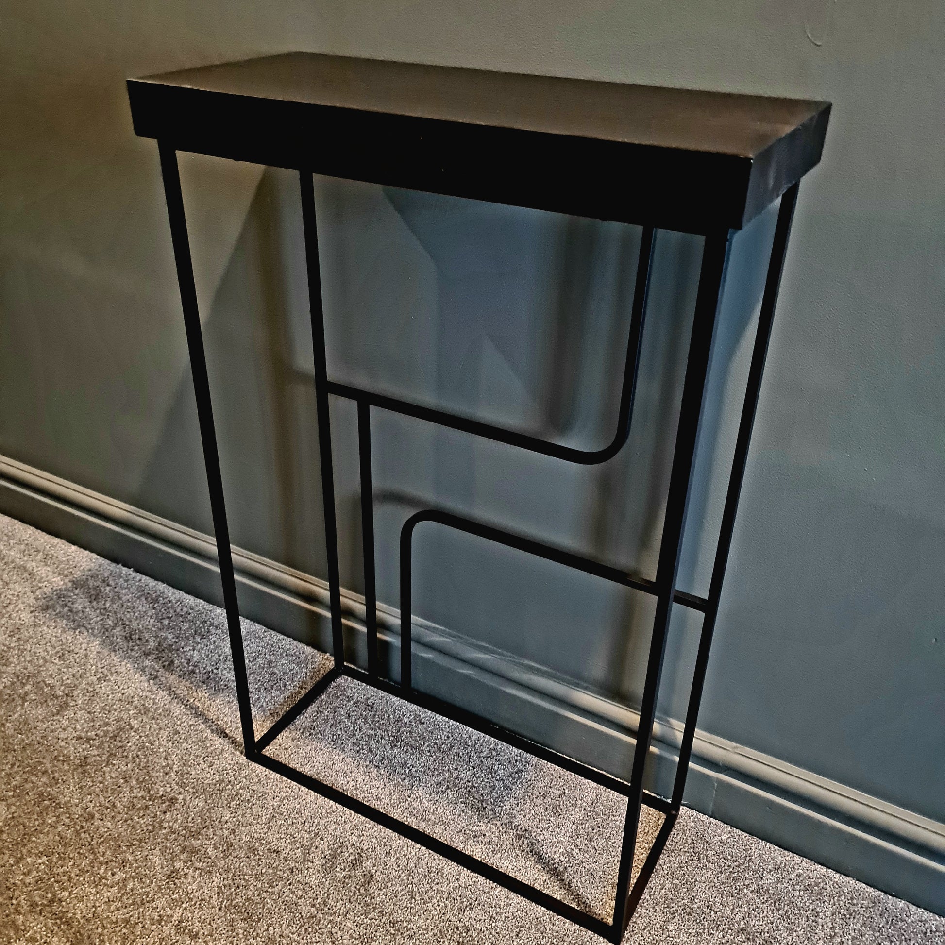 Black metal console table against a plain wall.