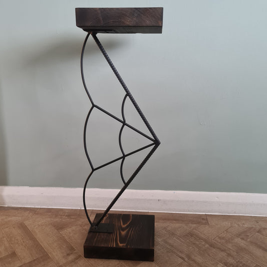 Decorative wall light with spider web design on a wooden bracket against a neutral wall.