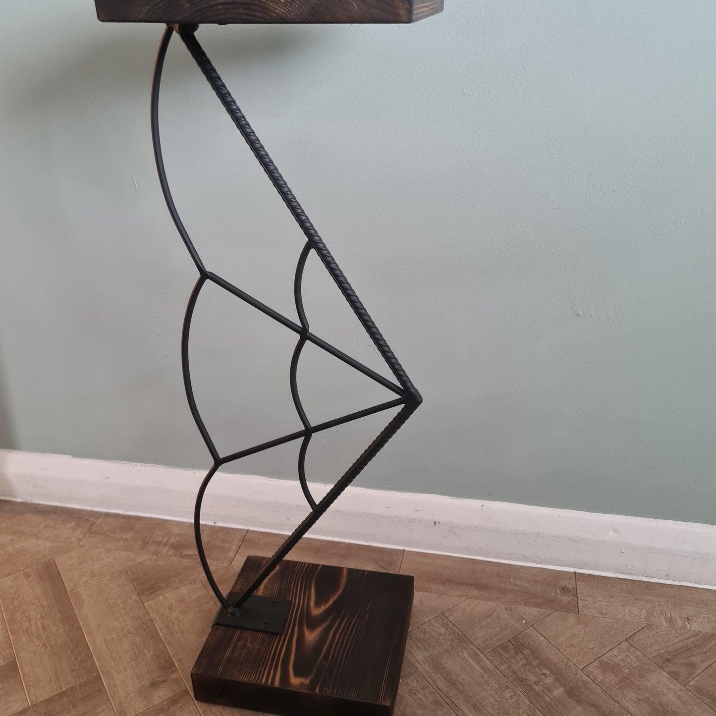 Wall-mounted metal bracket with wooden brackets on a light gray wall.