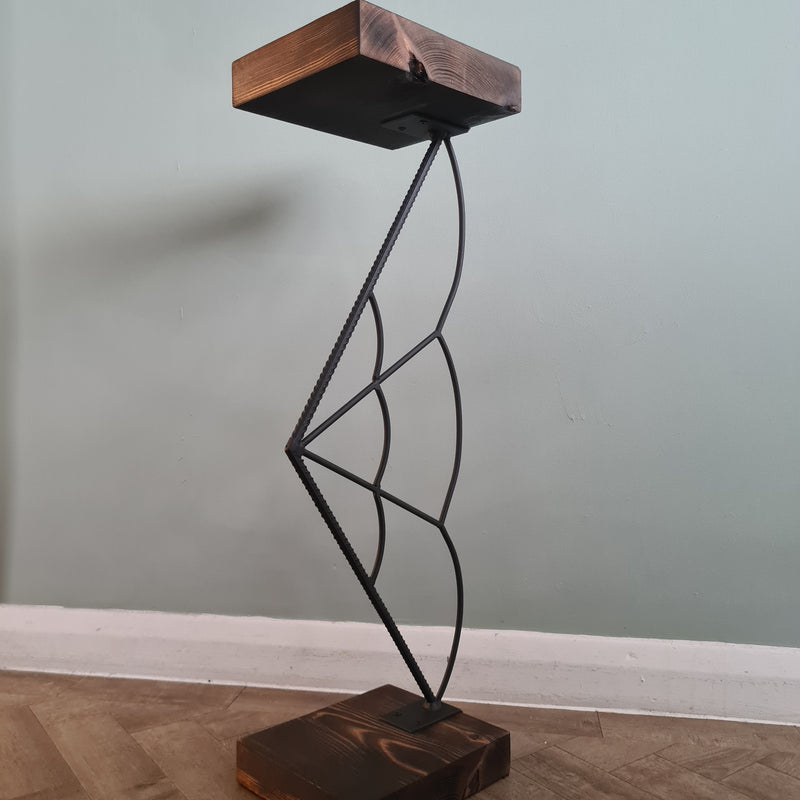 Wall-mounted metal shelf with wooden brackets against a light gray wall.