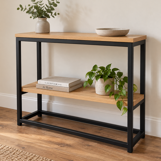 A two-tier console table with a light oak wood top and shelves, supported by a black metal frame, styled with books, a bowl, and potted plants in a home setting.